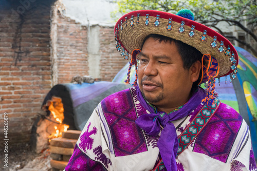 A close-up of a man from the Huichol tribe in Mexico and a temazcal in the background