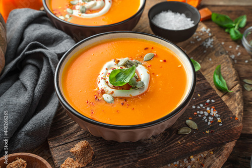 Autumn cream soup with cream and pumpkin seeds on a wooden background.