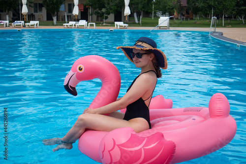 Woman on flamingo pool float in pool. Summer holidays, enjoying summer vacations during quarantine.