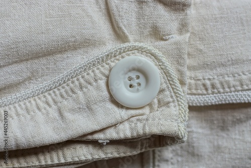 one big plastic white button on gray fabric sleeves on clothes