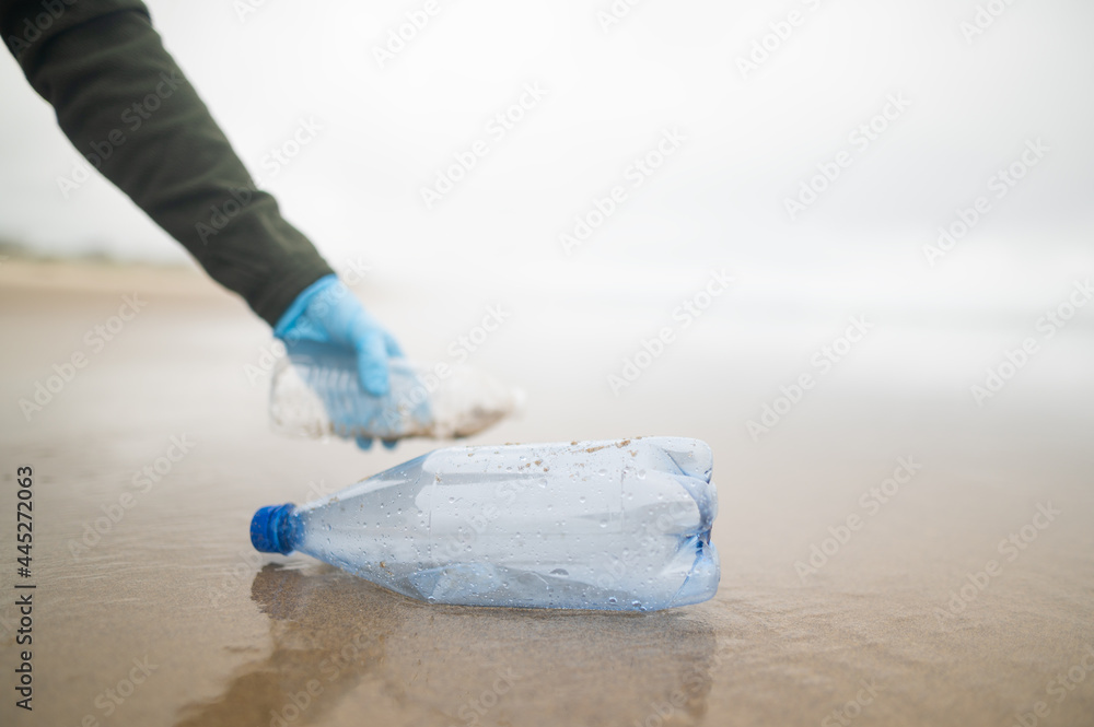 A plastic water bottle is lying on the ocean shore. Garbage collection. Conservation of the