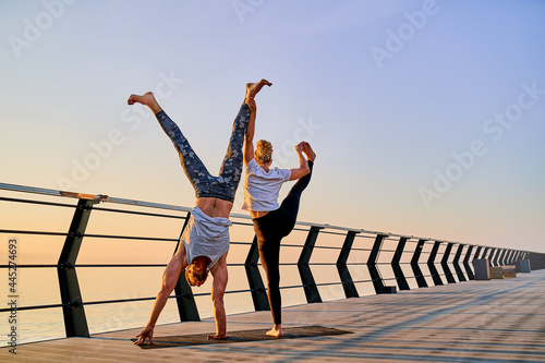 Couple doing practicing yoga together on nature outdoors . Morning exercises at the sunrise.