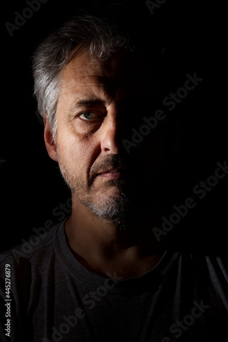 Fotografi low key portrait of man with half face in harsh shadows