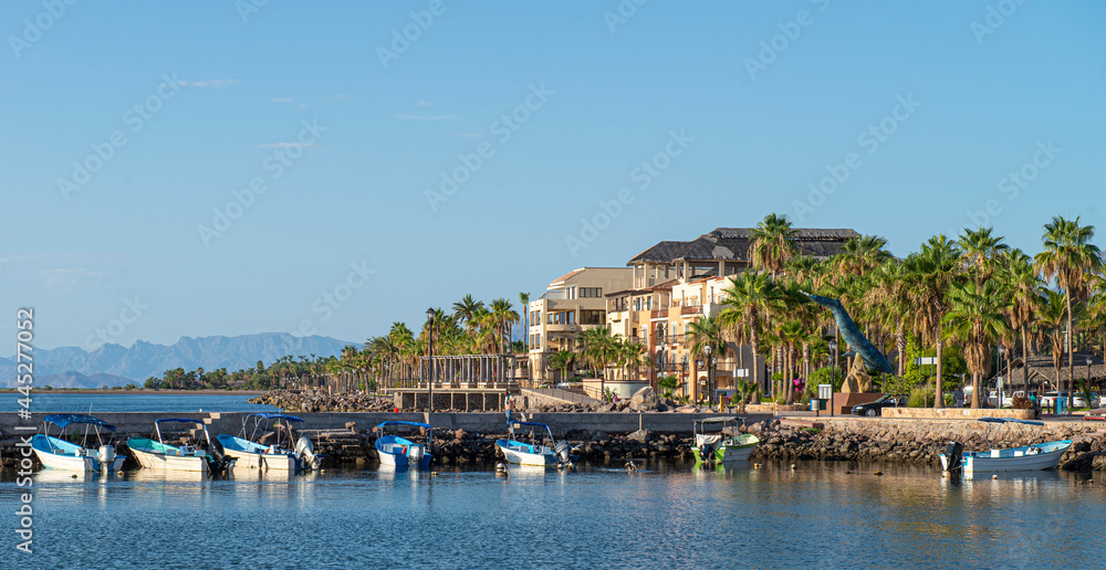 Pangas or boats on the bay of Loreto with architecture and palm trees on the Malecon in a sunny morning of summer, the Baja peninsula in the state of Baja California Sur. MEXICO