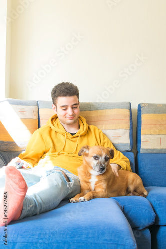 Young man smiling, spending time with his dog on the sofa. Pet love concept