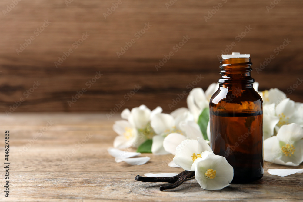 Jasmine essential oil and fresh flowers on wooden table, space for text Jasmine essential oil and fresh flowers on wooden table, space for text