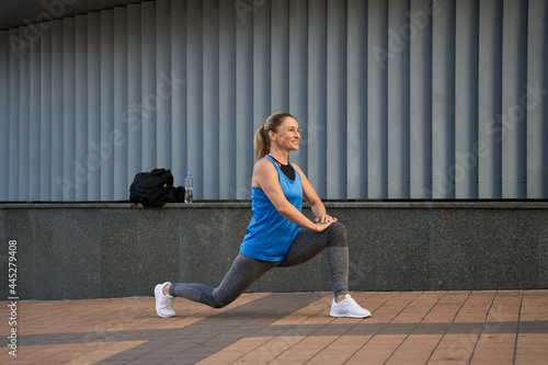 Full length shot of beautiful sportive mature woman in sportswear smiling away while warming up outdoors