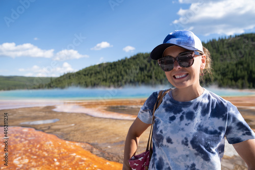 Woman wearing a blue tie die tshirt poses at Grand Prismatic Spring in Yellowstone National Park