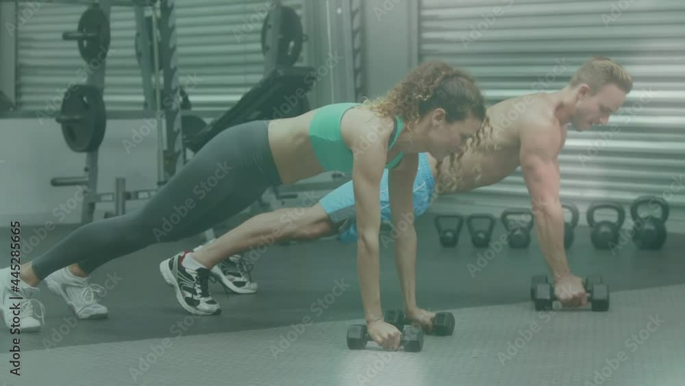 Animation of glowing light over fit man and woman exercising in gym Animation of glowing light over fit man and woman exercising in gym