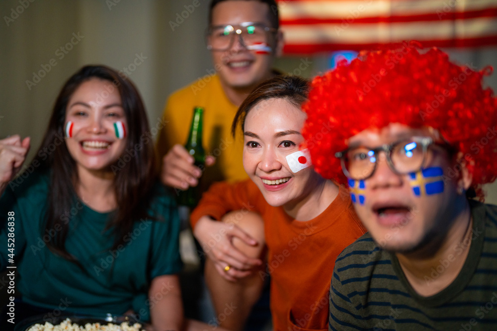 Group of Asian people friends sit on sofa watching and cheering sports games competition on TV together at home. Excited man and woman sport fans celebrate sport team victory in national sports match Group of Asian people friends sit on sofa watching and cheering sports games competition on TV together at home. Excited man and woman sport fans celebrate sport team victory in national sports match