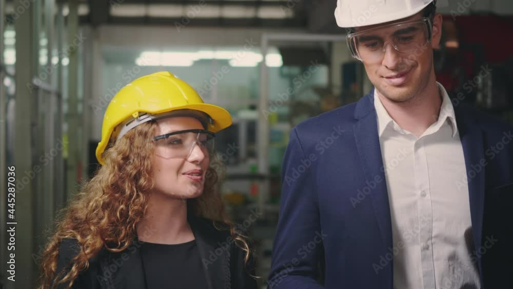Caucasian maintenance engineer man and diverse female factory workers in hardhats walking on plant floor and talking, Manager supervisor and industrial manufacturing, slow motion Caucasian maintenance engineer man and diverse female factory workers in hardhats walking on plant floor and talking, Manager supervisor and industrial manufacturing, slow motion