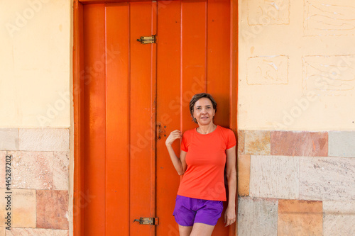 Lady Standing against an Orange Door with a matching Shirt