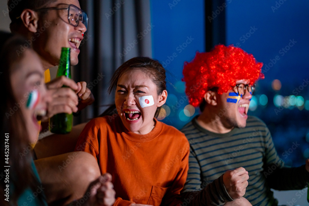 Group of Asian people friends sit on sofa watching and cheering sports games competition on TV together at home. Excited man and woman sport fans celebrate sport team victory in national sports match Group of Asian people friends sit on sofa watching and cheering sports games competition on TV together at home. Excited man and woman sport fans celebrate sport team victory in national sports match