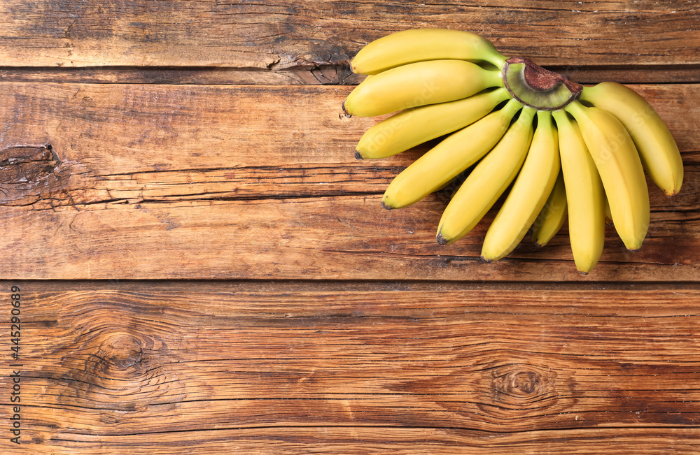 Bunch of ripe baby bananas on wooden table, top view. Space for text Bunch of ripe baby bananas on wooden table, top view. Space for text