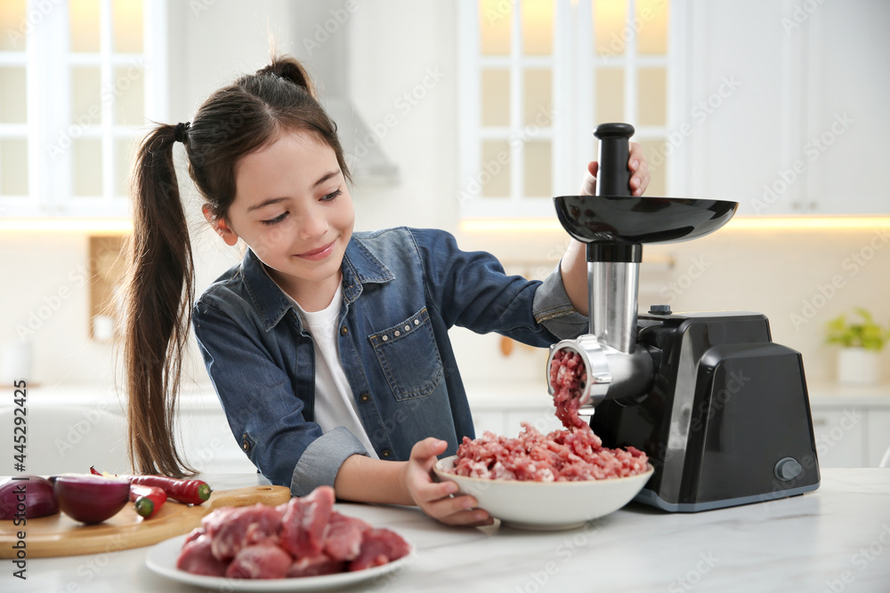 Little girl using modern meat grinder in kitchen Little girl using modern meat grinder in kitchen