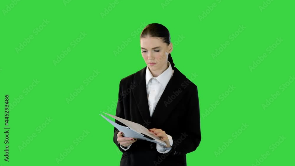 Young woman in office suit is getting ready to perform, looking into document on a Green Screen, Chroma Key. Young woman in office suit is getting ready to perform, looking into document on a Green Screen, Chroma Key.