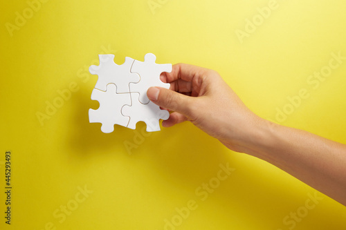 Hand holding puzzle pieces together in a conceptual image of teamwork and cooperation.