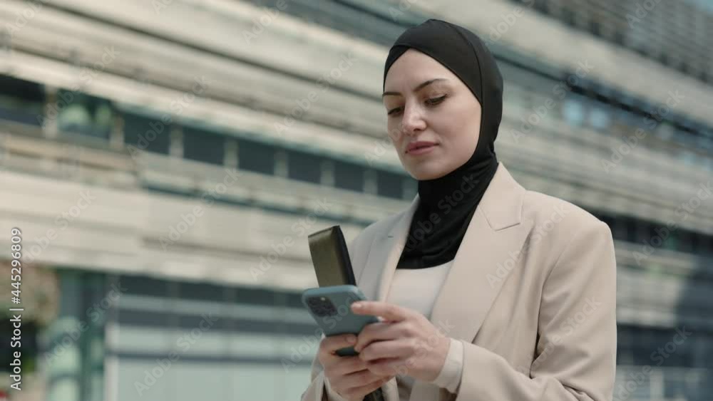 Arabian woman using smartphone while walking outdoors Arabian woman using smartphone while walking outdoors