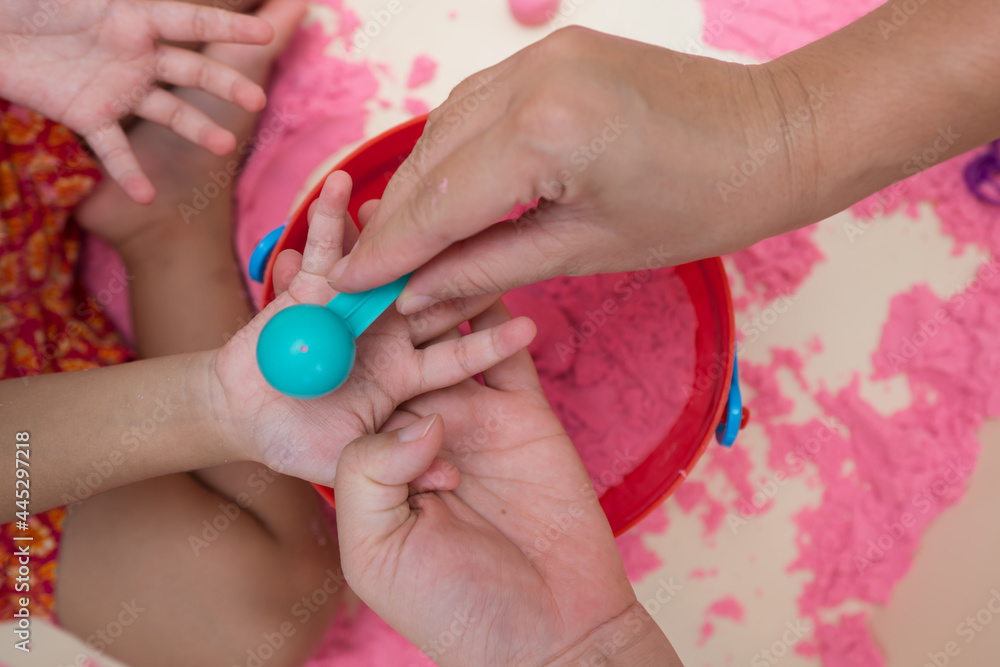 Children's hands playing pink science sand and various mould Children's hands playing pink science sand and various mould