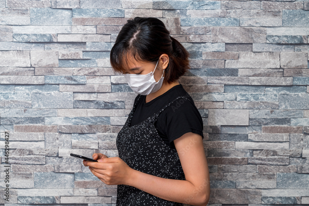 マスクをしてスマートフォンを使う若い女性 マスクをしてスマートフォンを使う若い女性