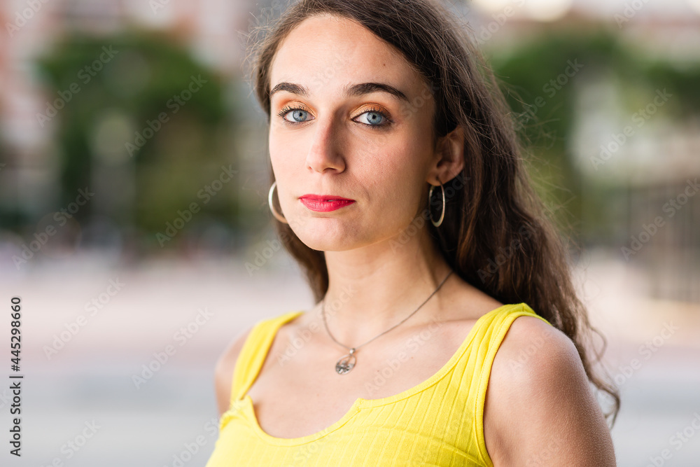 Hispanic young woman portrait outdoors looking at camera headshot. Yellow casual clothes Hispanic young woman portrait outdoors looking at camera headshot. Yellow casual clothes