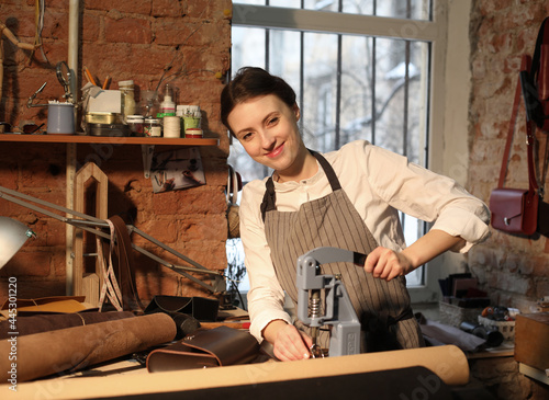 Leather handbag craftsman at work in a vintage workshop. Small business concept.