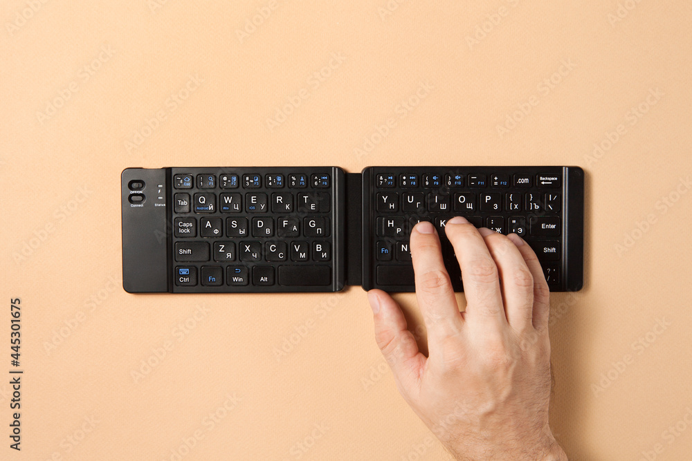 A man hand typing with wireless keyboard on the brown background A man hand typing with wireless keyboard on the brown background