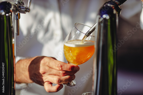 Obraz na płótnie Shallow depth of field (selective focus) image with a man pouring craft beer from a dispenser into a glass