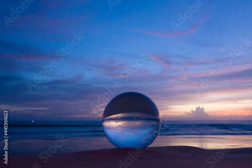 The natural view of the sea and sky in beautiful sunset are unconventional and beautiful inside crystal ball. .A image for a unique and creative travel. © Narong Niemhom