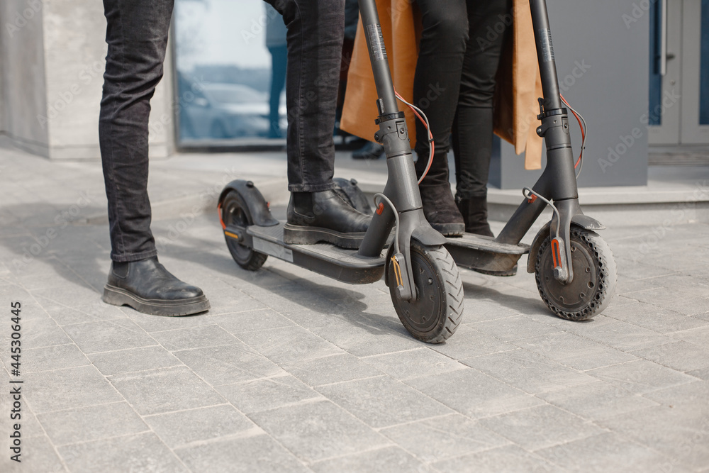 Obraz premium Interracial young couple with scooters in the city background