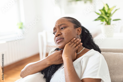 Close up of young woman rubbing her inflamed tonsils, tonsilitis problem, cropped. Woman with thyroid gland problem, touching her neck, girl has a sore throat photo