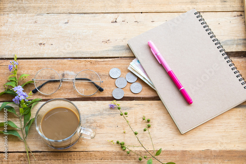 notebook ,cash ,coins and hot coffee of lifestyle woman arrangement flat lay style on background wooden