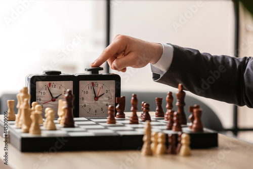 Man playing chess on wooden table, closeup photo