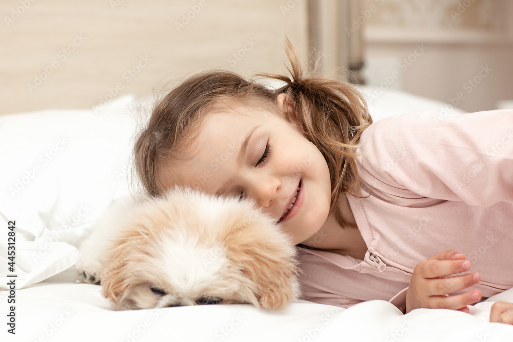 Child with baby dog. Kids play with puppy. Little girl and puppy dog sleep on bed at home. Pet at home. Animal care. Friendship between animal and children Child with baby dog. Kids play with puppy. Little girl and puppy dog sleep on bed at home. Pet at home. Animal care. Friendship between animal and children