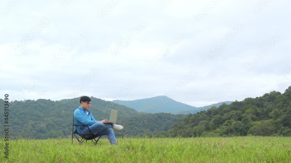Asian businessman working on laptop computer for online stock trading or small business on the mountain. Modern handsome man enjoy outdoor lifestyle with using wireless technology on summer vacation. Asian businessman working on laptop computer for online stock trading or small business on the mountain. Modern handsome man enjoy outdoor lifestyle with using wireless technology on summer vacation.