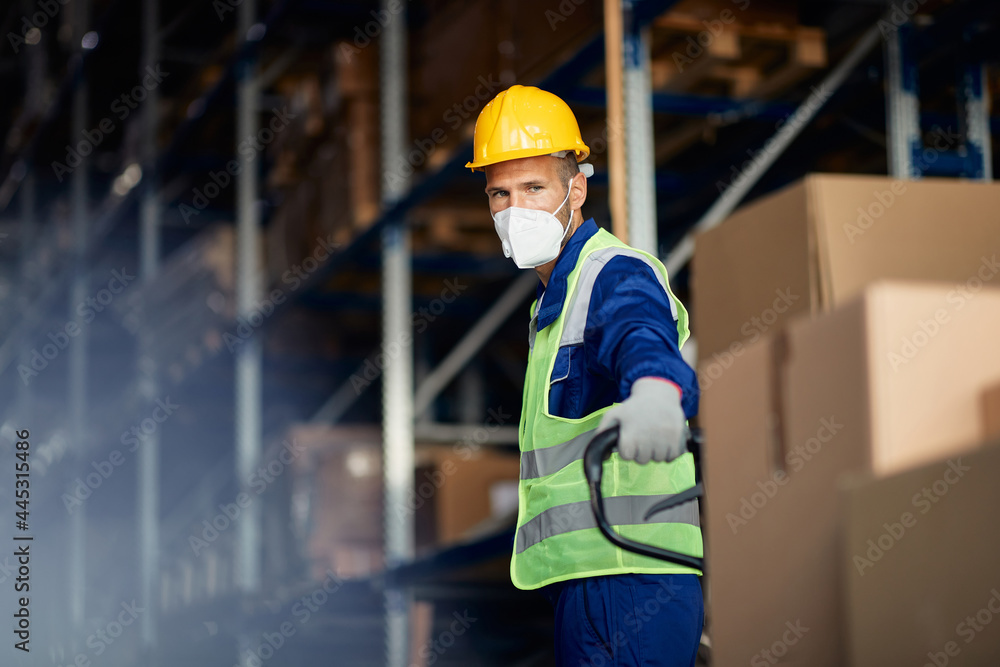 Warehouse worker pulls pallet jack while working at storage compartment during coronavirus pandemic. Warehouse worker pulls pallet jack while working at storage compartment during coronavirus pandemic.