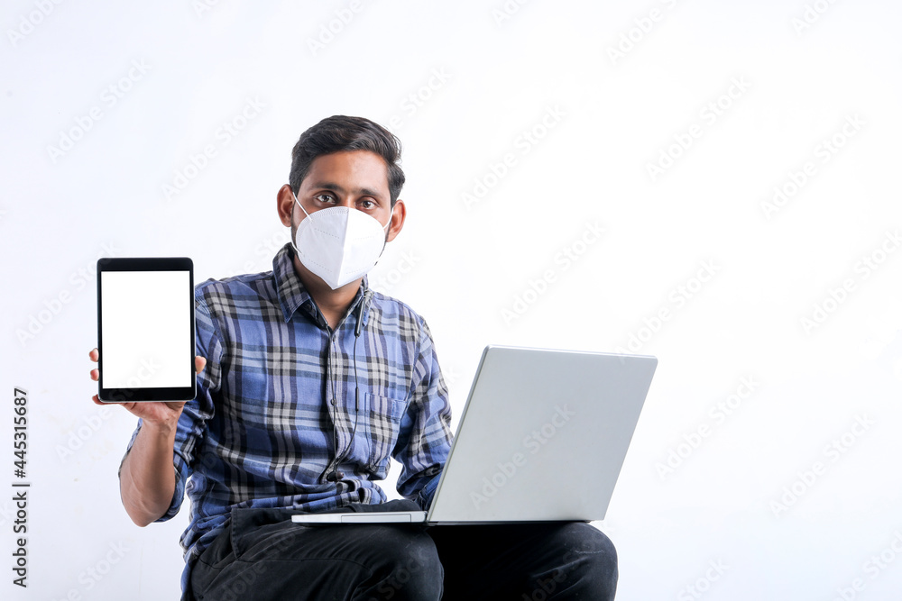 Young indian using laptop and showing tablet over white background.