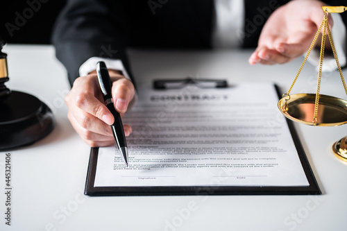 Close up of view Business woman or Female lawyer recommend to sign contract paper with Judge gavel, brass scale on a desk at law firm office, law, and justice concept.