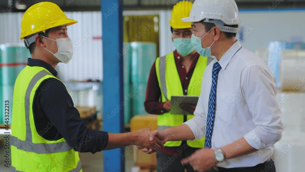 engineer and  workers  workplace in warehouse. they wear mask face sanitation during COVID-19 pandemic. After standing and talking, shake hands to congratulate. shipping, logistics, business concept.