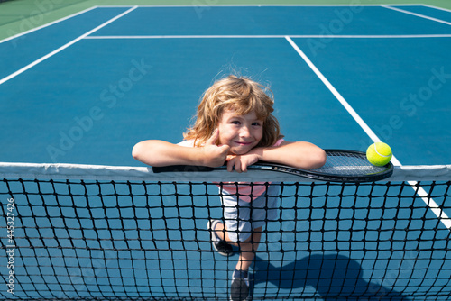 Child boy with tennis racket and ball on tennis court outdoor. Sport exercise for kids. Summer activities for children. © Volodymyr