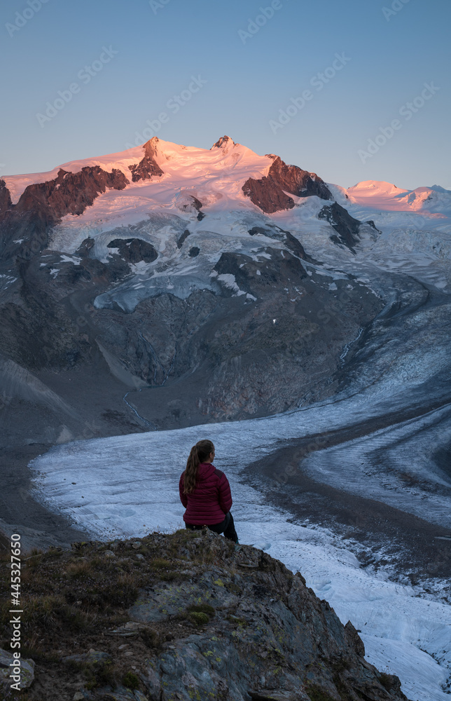 A woman looking over the Gorner glacier at the mountains during sunset.