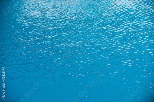 Water background, ripple waves. Blue swiming pool pattern. Sea surface. Water in swimming pool with sun reflection. Banner with copy space.