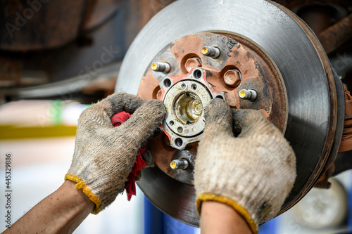 Fotografie car repair service Mechanic is putting lubricating grease into bearings and assembling new car bearings