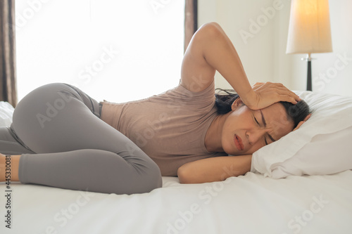 hangover girl sleeps with headache. unhappy woman feeling headache after sudden awakening by phone call,alarm in early morning, exhausted young female suffering from insomnia or migraine,lying in bed