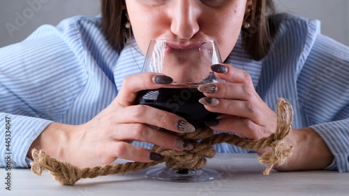 female funny drinks from a wine glass tied with a jute rope. The concept of alcohol addiction. The problem of alcoholism treatment