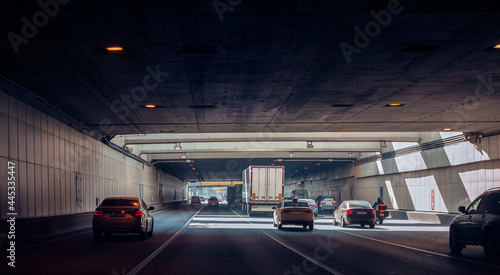 Cars and a motorcycle are driving in the tunnel under the road