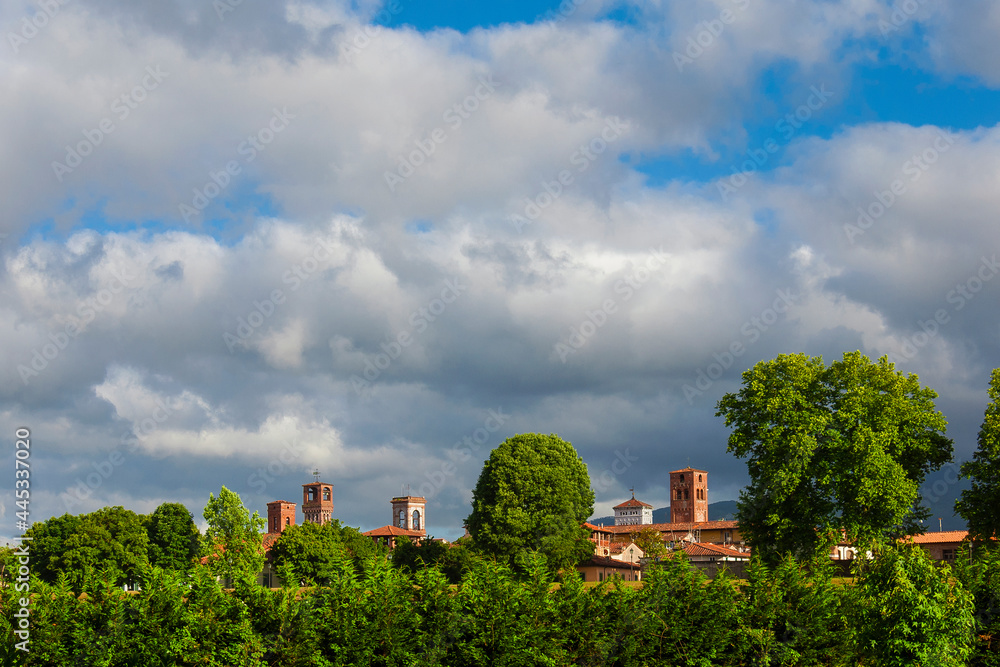 Lucca charming historic center skyline with beautiful clouds and medieval towers rises above surrounding anciet walls park trees