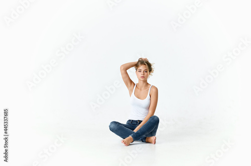 woman in white t-shirt and jeans sits on the floor holding her hair © SHOTPRIME STUDIO