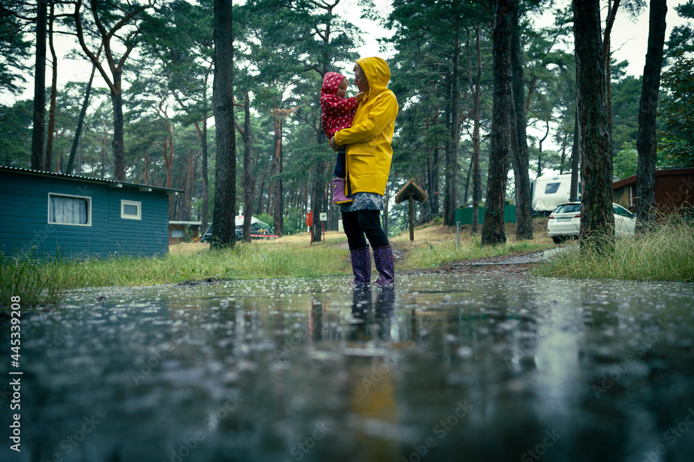 Unwetter - Nach heftigen Regen stehen Frau und Kind im Wasser - obrazy, fototapety, plakaty 