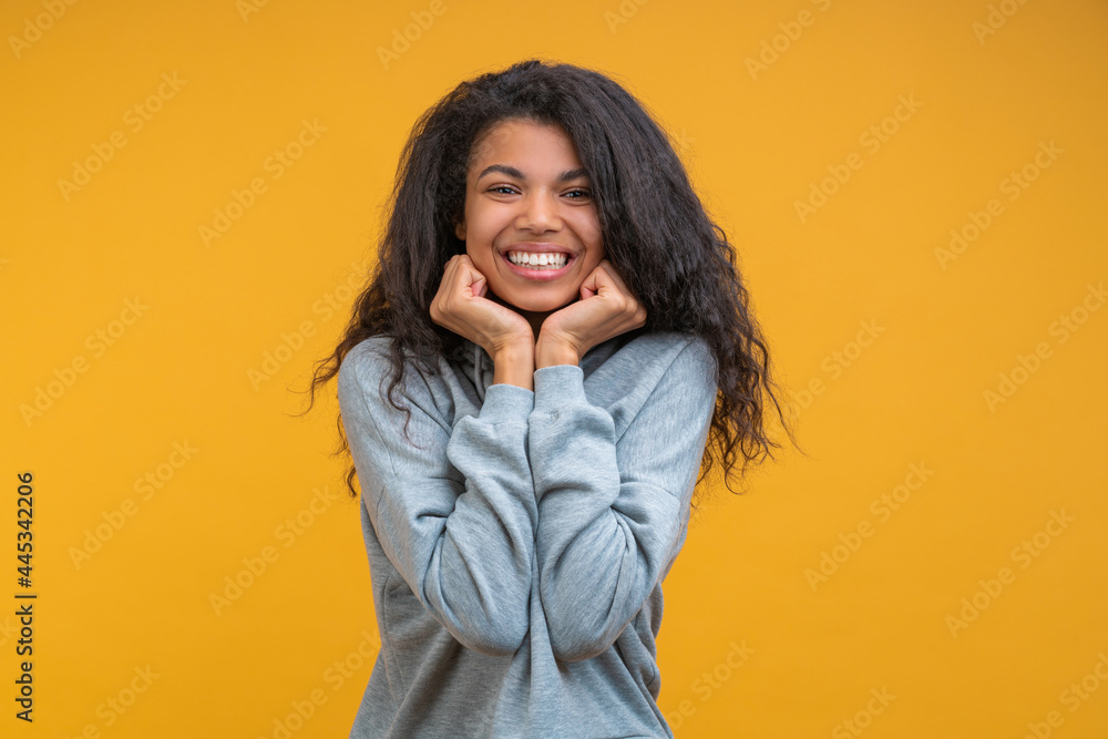 Studio portrait of happy young casually dressed african american girl isolated over bright colored orange yellow background Studio portrait of happy young casually dressed african american girl isolated over bright colored orange yellow background